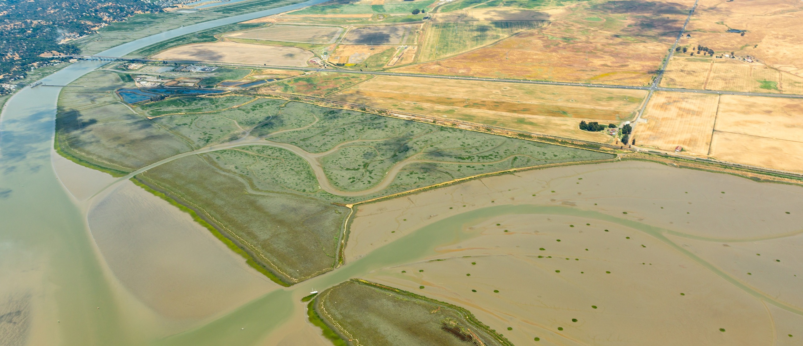 Aerial view of marsh and farmland by a river